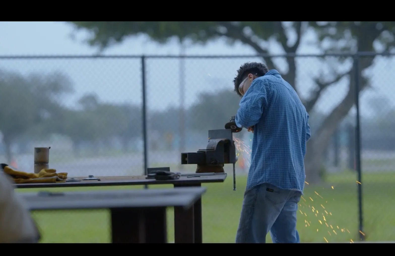 Student learning metalworking outdoors with an instructor